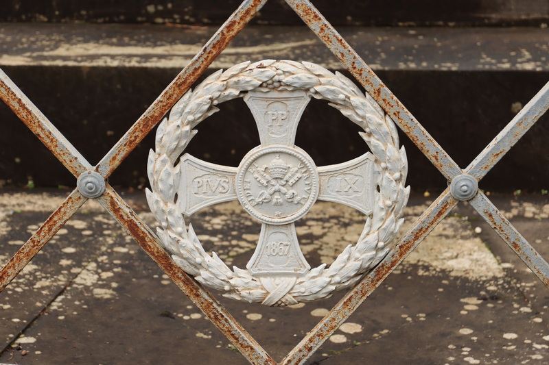 Het pauselijk wapen op het hekwerk rond het monument op Campo Verano